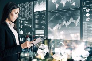 A professional in a suit holds a tablet while interacting with holographic data displays featuring graphs, charts, and world maps.