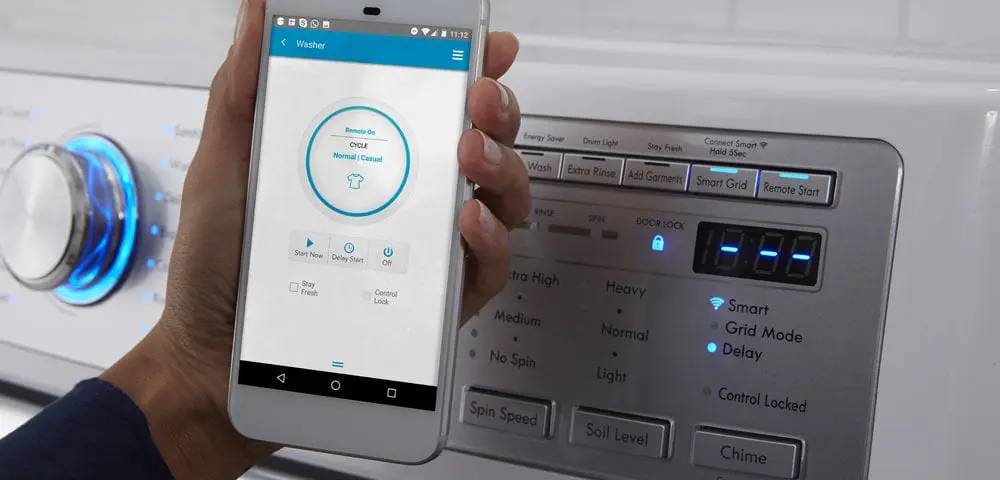 A person using a smartphone app to control a washing machine, showing settings for wash cycles and remote start.