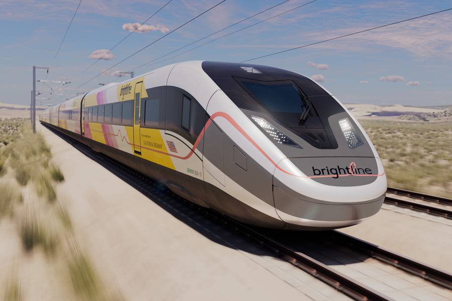 A sleek, modern Brightline train in vibrant colors speeds along tracks through a desert landscape under a clear blue sky.