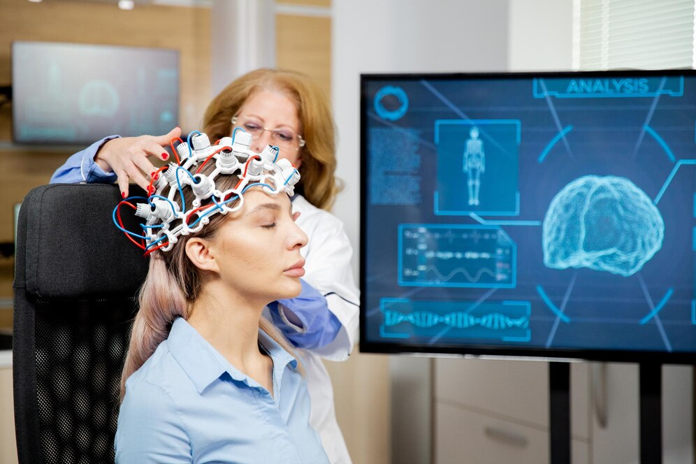  A healthcare professional attaches sensors to a patient's head while a digital screen displays brain analysis data and visualizations.