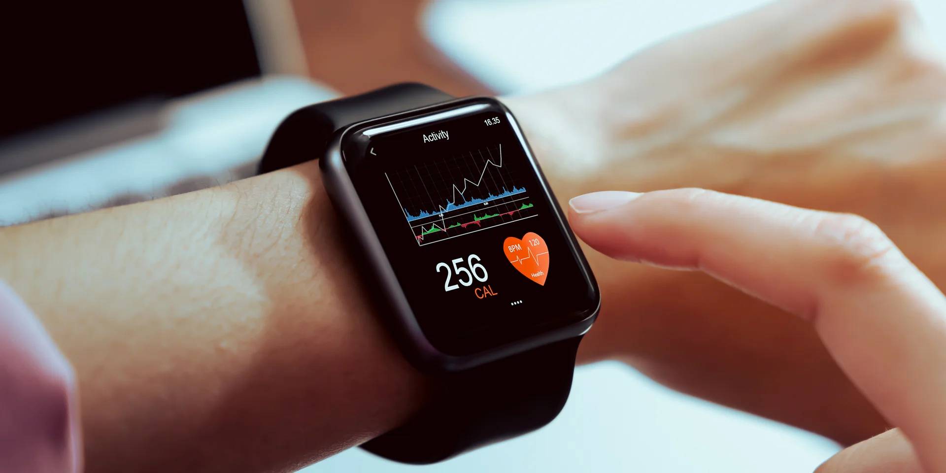 A close-up of a smartwatch display showing activity stats: 256 calories burned and a heart rate of 120 BPM. A finger is tapping the screen.