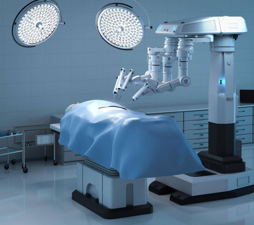 A robotic surgical system is poised over a patient on an operating table, illuminated by bright surgical lights.