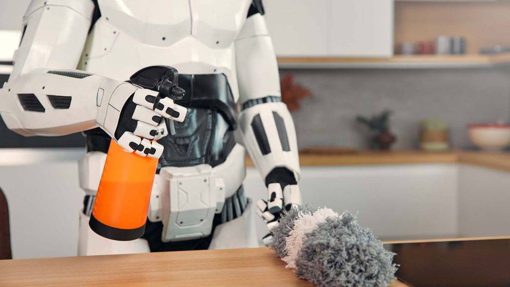 A futuristic robot holding an orange spray bottle, poised above a fur duster on a wooden table in a modern kitchen setting.