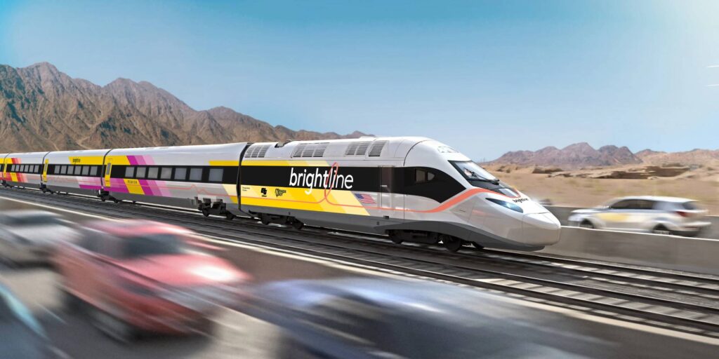 A sleek Brightline high-speed train travels through a desert landscape, alongside a blur of moving cars on a parallel road.