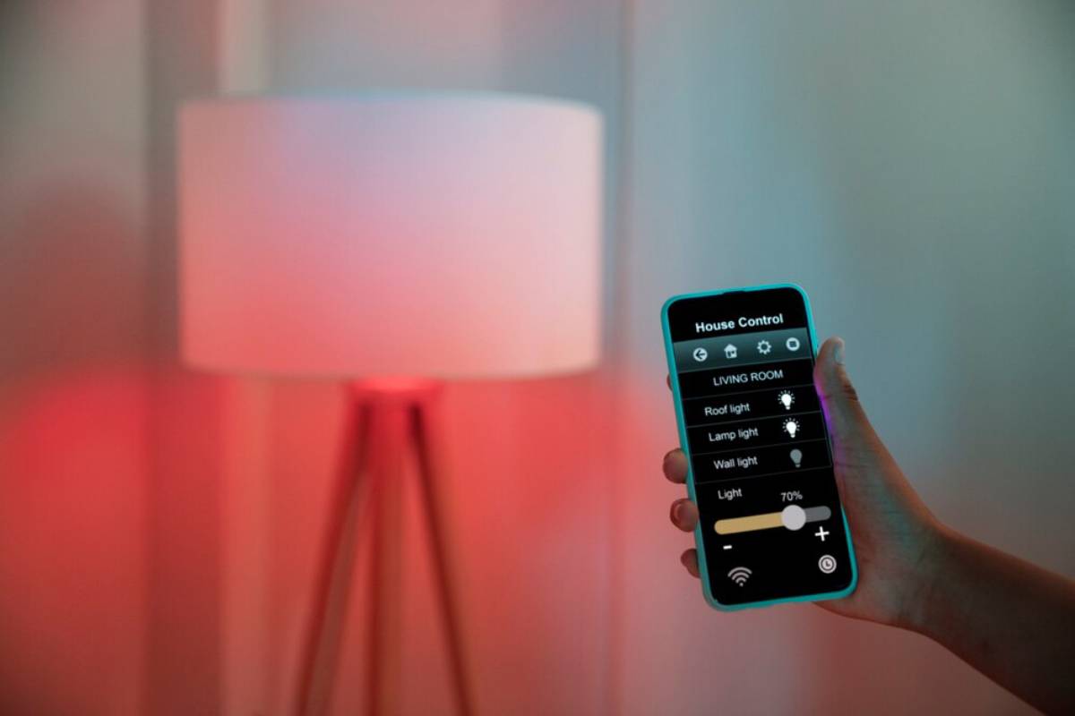   A person holding a smartphone in front of a lamp, showcasing the device's screen illuminated by the lamp's light.