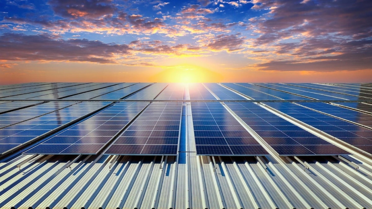 Solar panels capture sunlight at sunrise, reflecting vibrant colors from the sky, symbolizing renewable energy and sustainability.